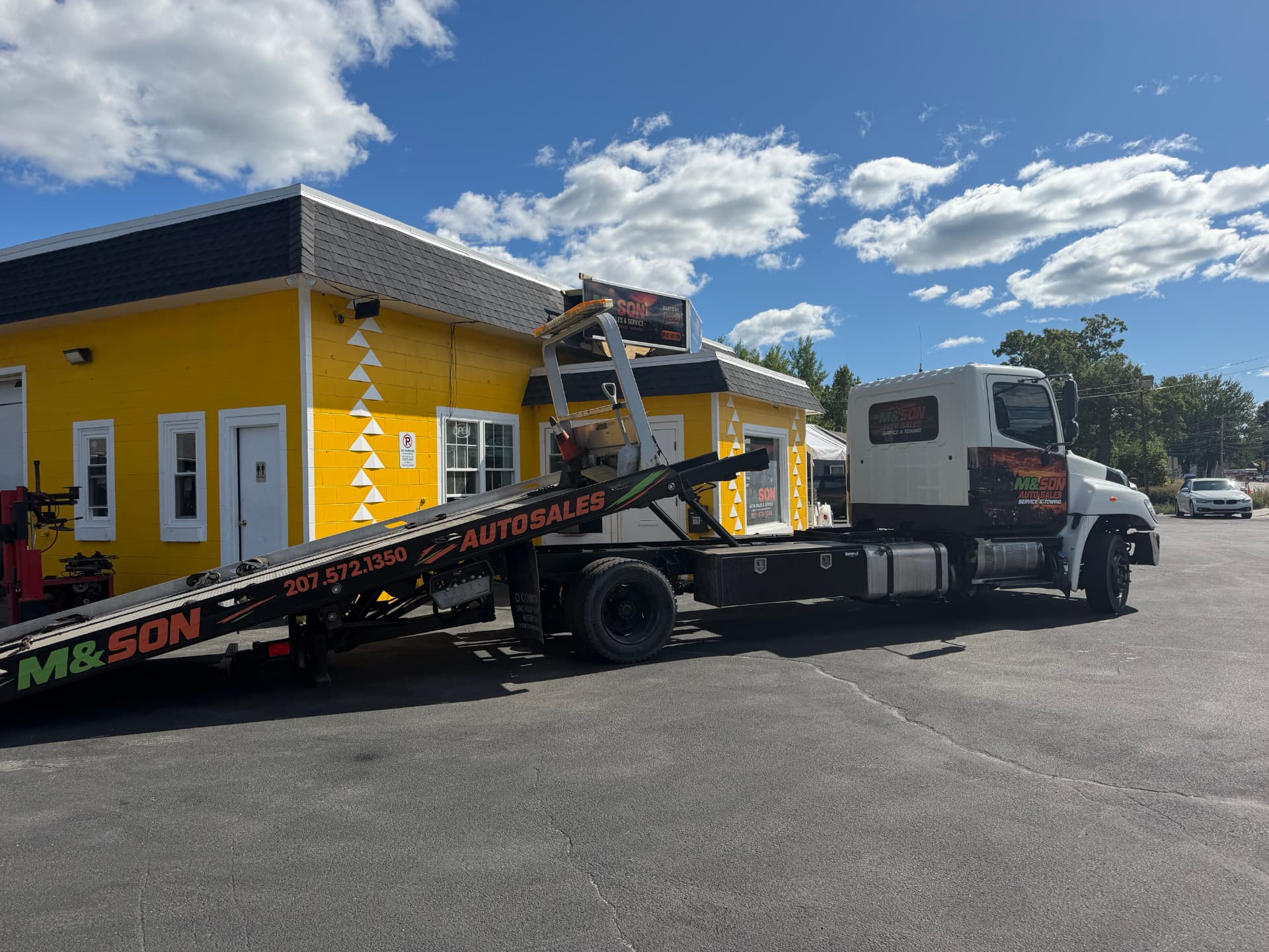 M & Son flatbed tow truck in front of the yellow shop on Roosevelt Trail in Windham, Maine